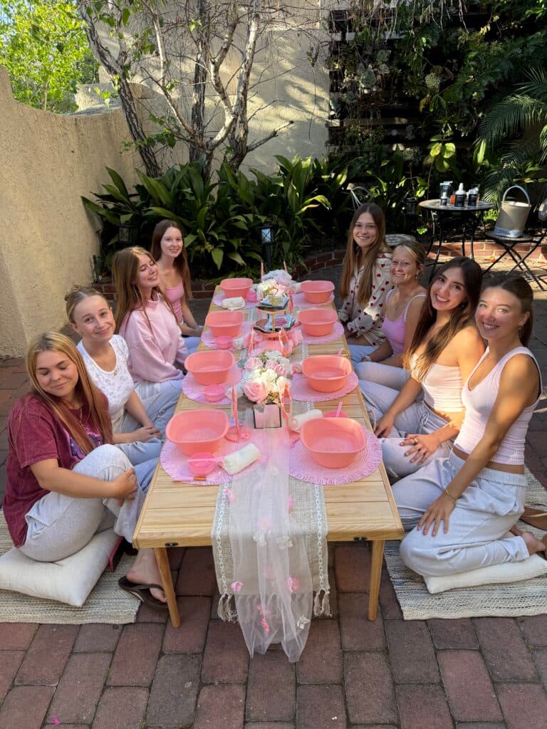Guests gathered around a pink themed spa table outdoors.