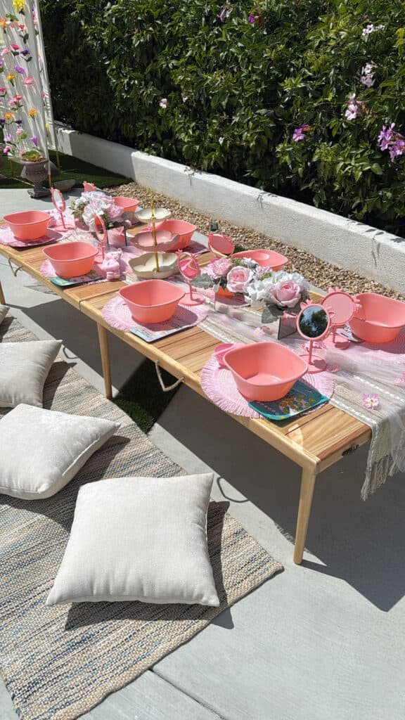 An outdoor spa table set with pink basins and pillows.